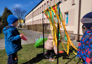 Chłopiec pochylając się przechodzi przez "kolorowe drzwi" z pasków bibuły.