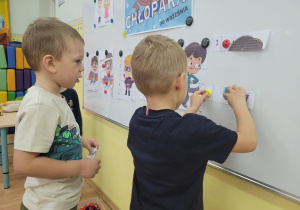 Dwaj chłopcy układają puzzle na tablicy magnetycznej.