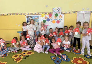 Grupa dzieci pozuję do zdjęcia z wykonanymi przez siebie muchomorkami z papieru