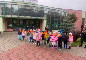 Przedszkolaki z grupy "Tygryski" stoją przed wejściem do budynku.