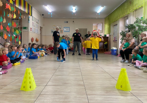 Chłopcy w zielonej i żółtej koszulce przekładają przez siebie szarfę.