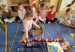 Dziewczynka mierzy wielkość chłopca za pomocą jabłek.