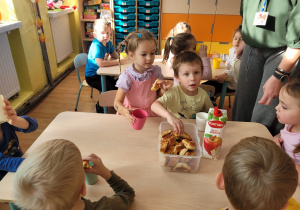 . Chłopiec w żółtej koszulce stempluje połową jabłka.