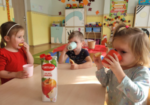 Dzieci piją sok jabłkowy i częstują się rogalikami.
