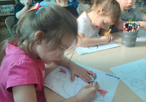 Dziewczynka w różowej bluzce koloruje obrazek