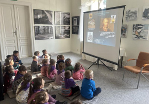 Dzieci słuchają ciekawostek o ekspozycji znajdującej się w muzeum.