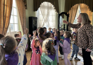 Dzieci słuchają ciekawostek o ekspozycji znajdującej się w muzeum.