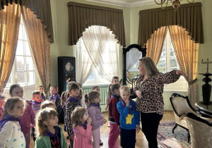 Dzieci słuchają ciekawostek o ekspozycji znajdującej się w muzeum.