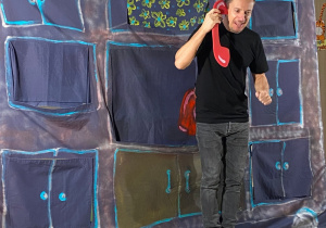 Aktor trzyma w ręku "słuchawkę telefonu" i prowadzi rozmowę.