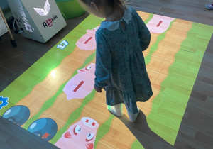 Dziewczynka zbija stopą świnki-skarbonki.