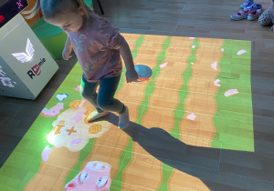 Dziewczynka zbija stopą świnki- skarbonki.