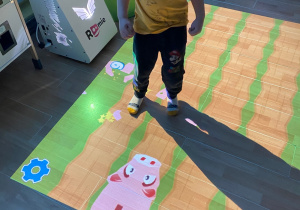 Chłopiec zbija stopą świnki- skarbonki.