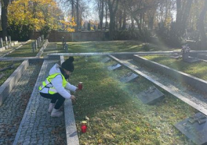 Dziecko stawia znicz na grobie