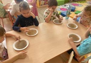 Dziewczynki dotykają pieprzu rozsypanego na wodzie.