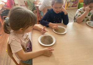 Dzieci dotykają pieprzu palcem umoczonym w mydle w płynie. Pieprz „ ucieka” od mydła