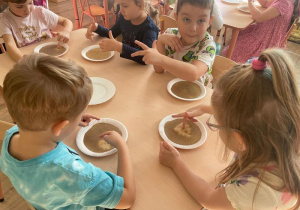 Dzieci dotykają pieprzu palcem umoczonym w mydle w płynie. Pieprz „ ucieka” od mydła