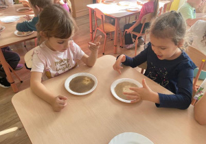 Dzieci dotykają pieprzu palcem umoczonym w mydle w płynie. Pieprz „ ucieka” od mydła