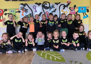 Pamiątkowe zdjęcie wszystkich dzieci na tle andrzejkowej dekoracji.