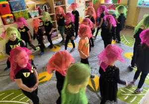 Dzieci biegają z neonowymi chustkami na głowie, udając duszki.