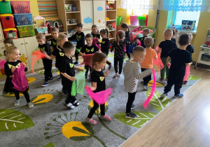 Dzieci biegają z neonowymi chustkami na głowie, udając duszki.