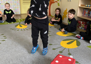 Dzieci rzucają dużą kostką.