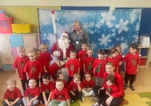 Wspólne zdjęcie dzieci z Mikołajem - dzieci ubrane na czerwono.