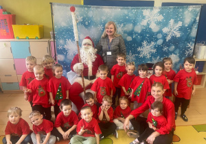 Wspólne zdjęcie dzieci z Mikołajem - dzieci ubrane na czerwono.