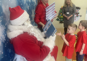 "Mikołaj" wręcza chłopcu upominek.