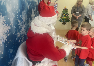 "Mikołaj" wręcza chłopcu upominek.