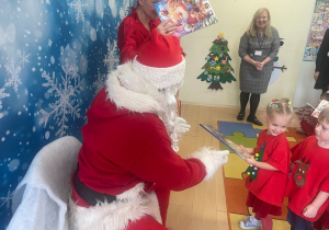"Mikołaj" wręcza dziewczynce upominek.