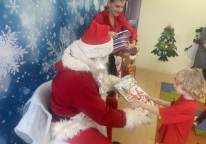 "Mikołaj" wręcza chłopcu upominek.