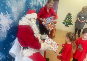 "Mikołaj" wręcza dziewczynce upominek.
