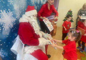 "Mikołaj" wręcza dziewczynce upominek.