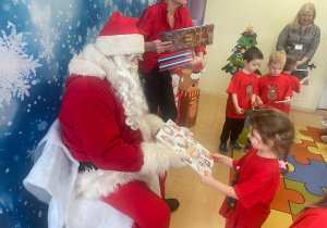 "Mikołaj" wręcza dziewczynce upominek.