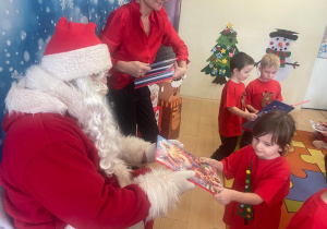 "Mikołaj" wręcza dziewczynce upominek.