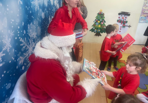 "Mikołaj" wręcza dziewczynce upominek.
