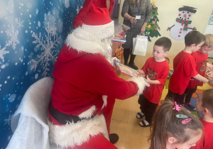 "Mikołaj" wręcza chłopcu upominek.