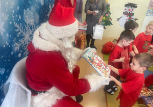 "Mikołaj" wręcza chłopcu upominek.