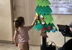 Dziewczynka ozdabia choinkę.