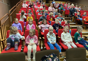 Dzieci siedzące na widowni w oczekiwaniu na rozpoczęcie projekcji filmu.