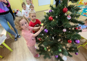 Dzieci zawieszają ozdoby na choince