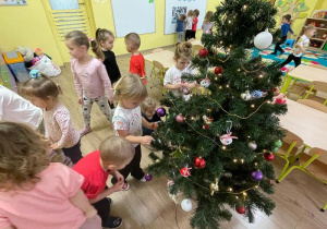 Dzieci zawieszają ozdoby na choince