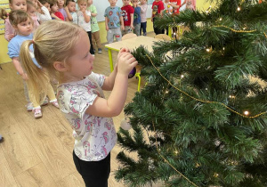 Dziewczynka wiesza ozdoby na choince
