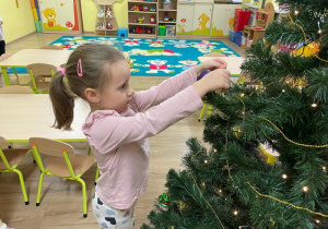 Dziewczynka wiesza ozdoby na choince