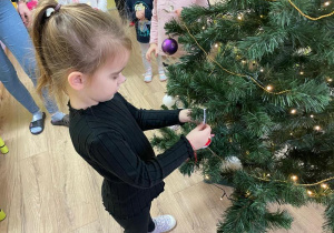 Dziewczynka wiesza ozdoby na choince