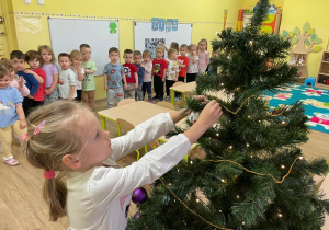 Dziewczynka wiesza ozdoby na choince