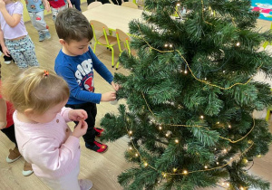 Dzieci zawieszają ozdoby na choince