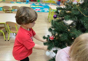 Chłopiec ozdabia choinkę