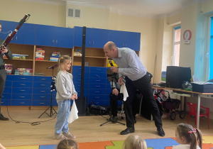 Dziewczyna wraz z panem Maciejem tańczą do muzyki Mozarta, trzymają w dłoniach białe chusteczki.