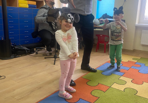 Dziewczynka z opaską myszki i chłopiec z opaską kota tańczą do melodii granej na fagocie